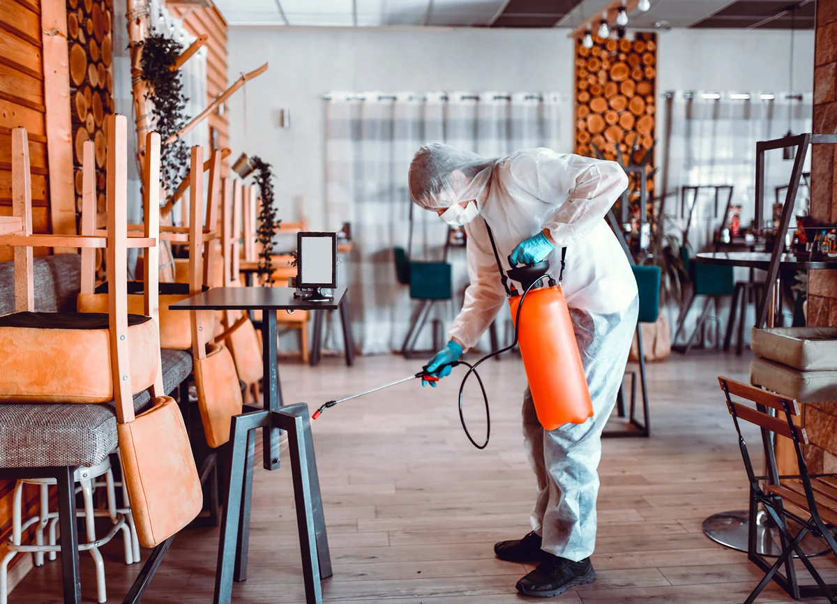 Worker sanitizing dining area with equipment